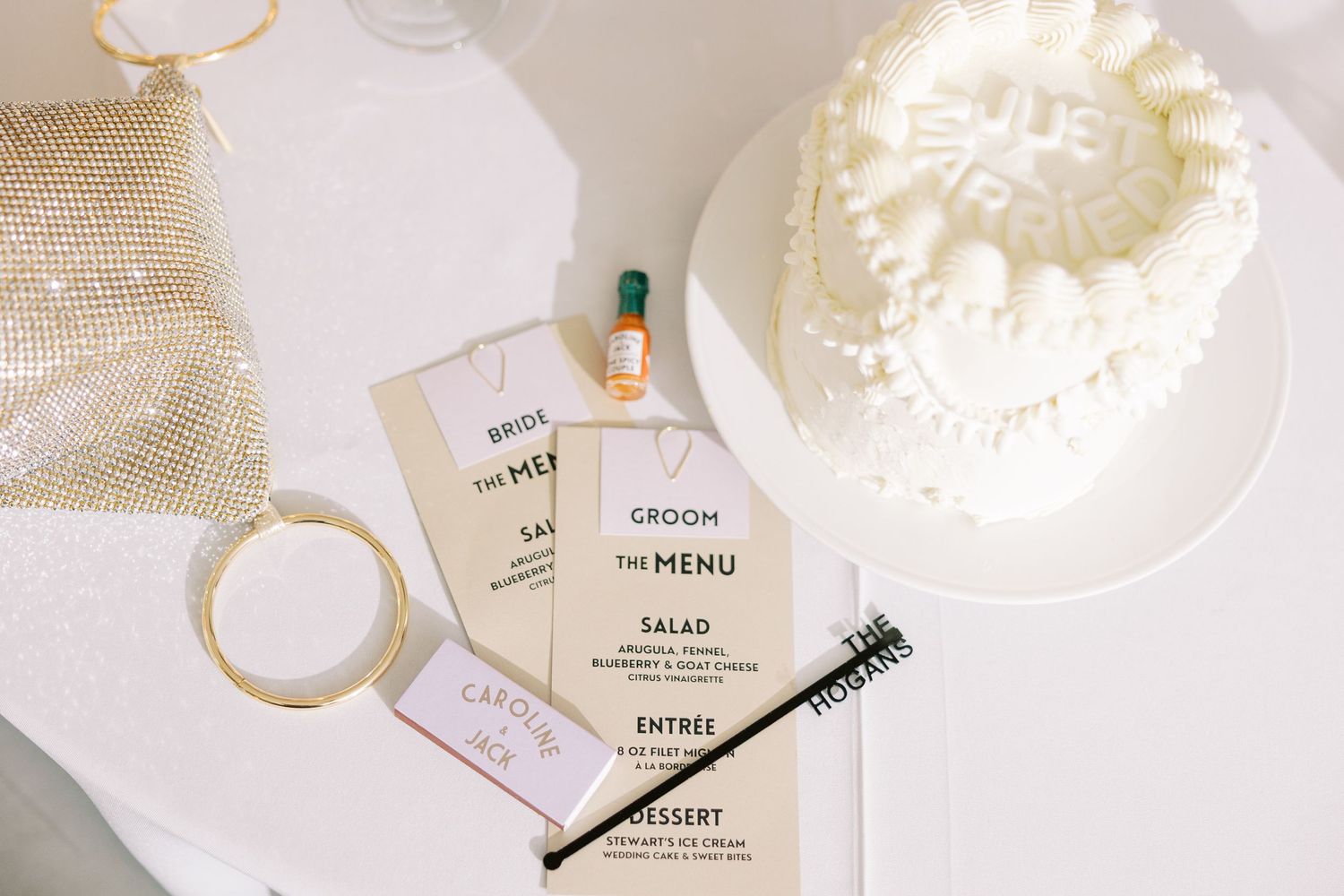 Wedding menu cards and invitation stationery displayed with a white wedding cake on white surface.