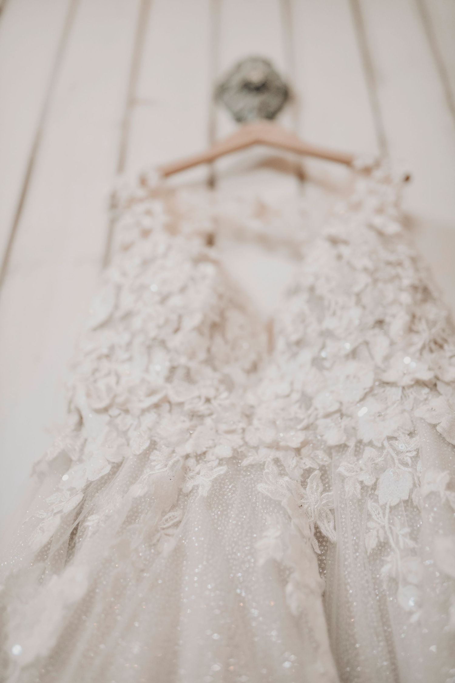 Wedding gown hanging from a chandelier in a rustic bridal suite