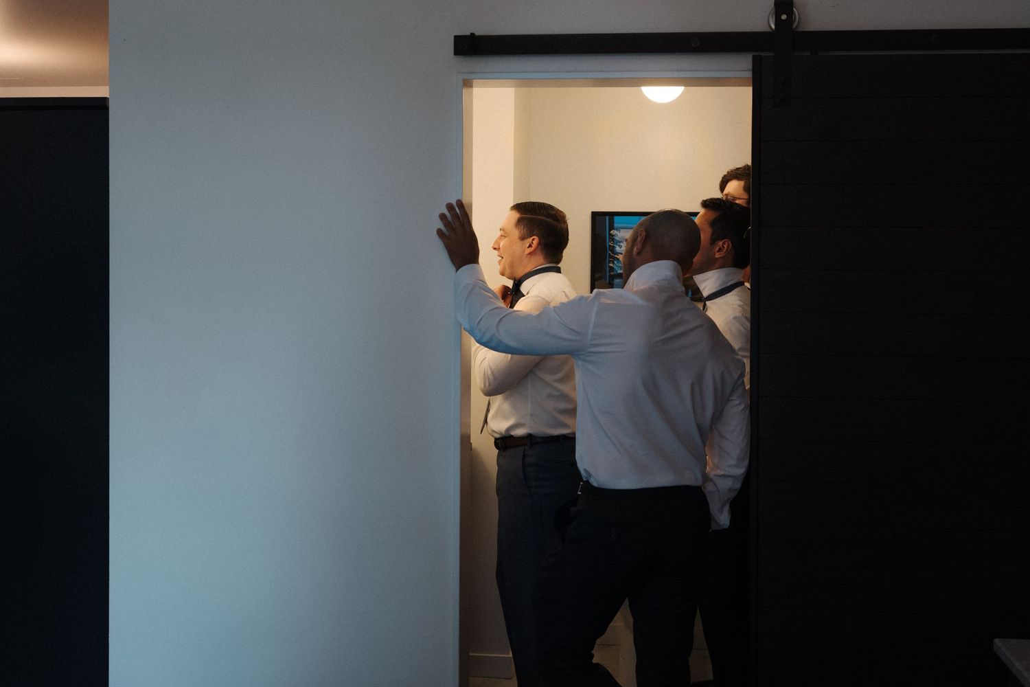 A sequence showing someone mounting a large piece of artwork or a display panel on a dark wall.