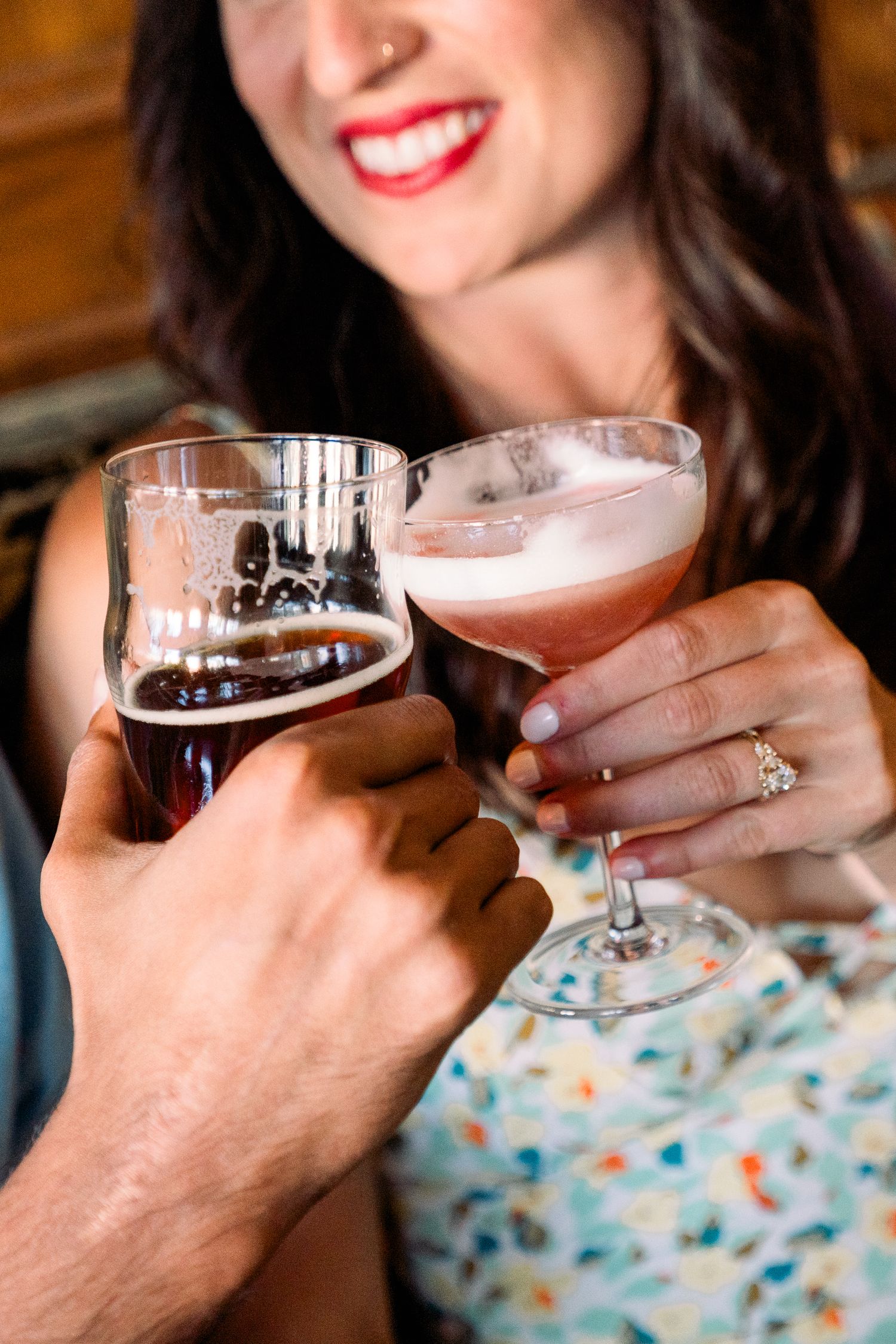 Two people toasting with cocktail glasses while enjoying drinks at a bar.