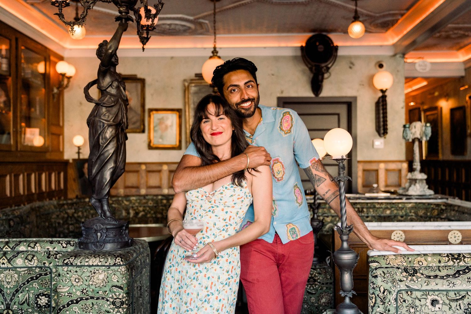 Couple embracing in a romantic restaurant interior with ornate decor and decorative statues.
