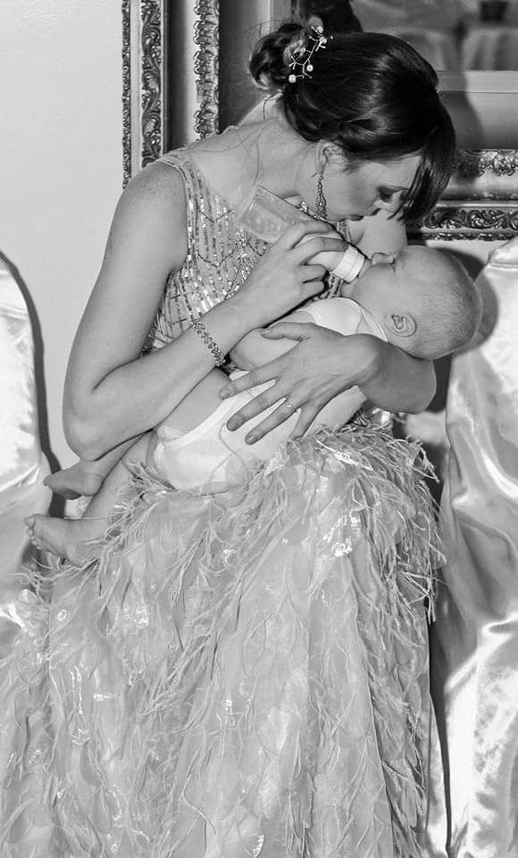 A tender moment captured in black and white as a baby and person in an ornate beaded gown share an intimate embrace.