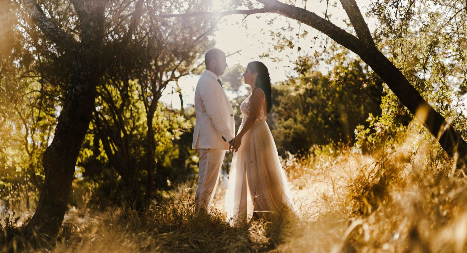 A romantic silhouette of a couple standing together in a magical golden sunset light filtering through trees.