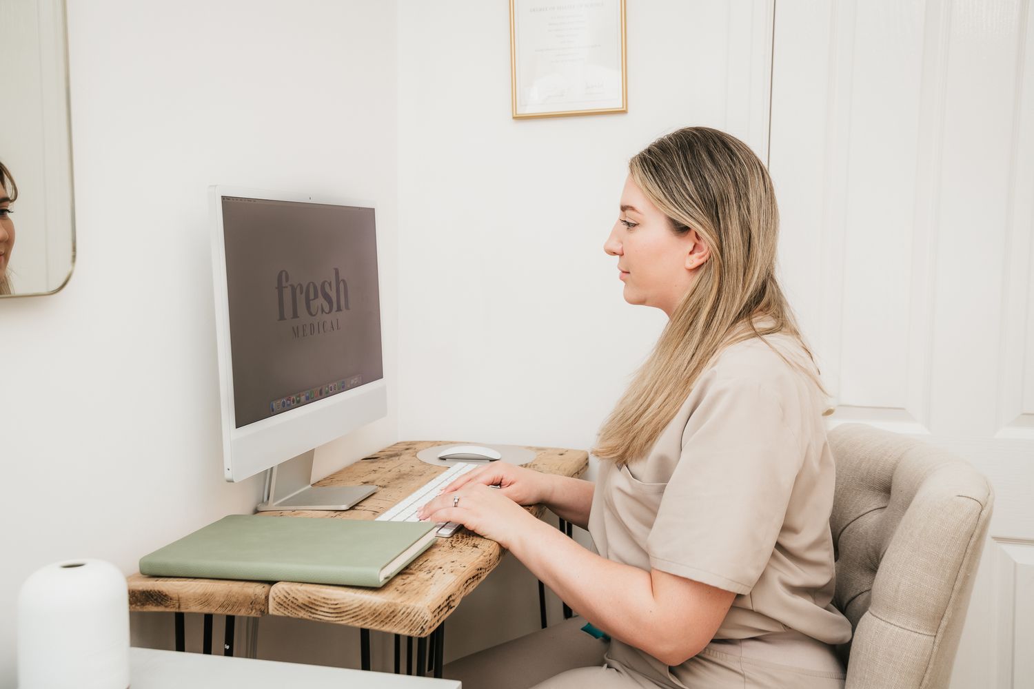 Someone types at a computer on a wooden laptop stand with a white coffee mug on their desk.
