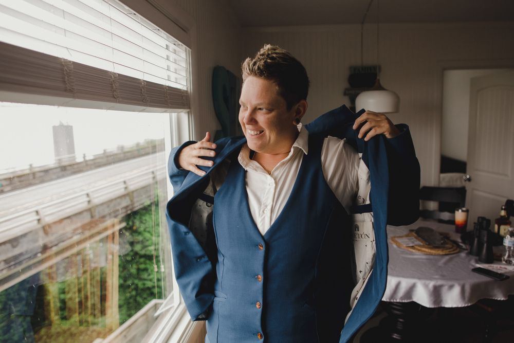 Someone getting dressed in formal attire near a window with natural light streaming in.