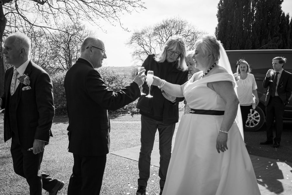 Wedding guests and officiant gather outdoors for a ceremony on a winter day in black and white.