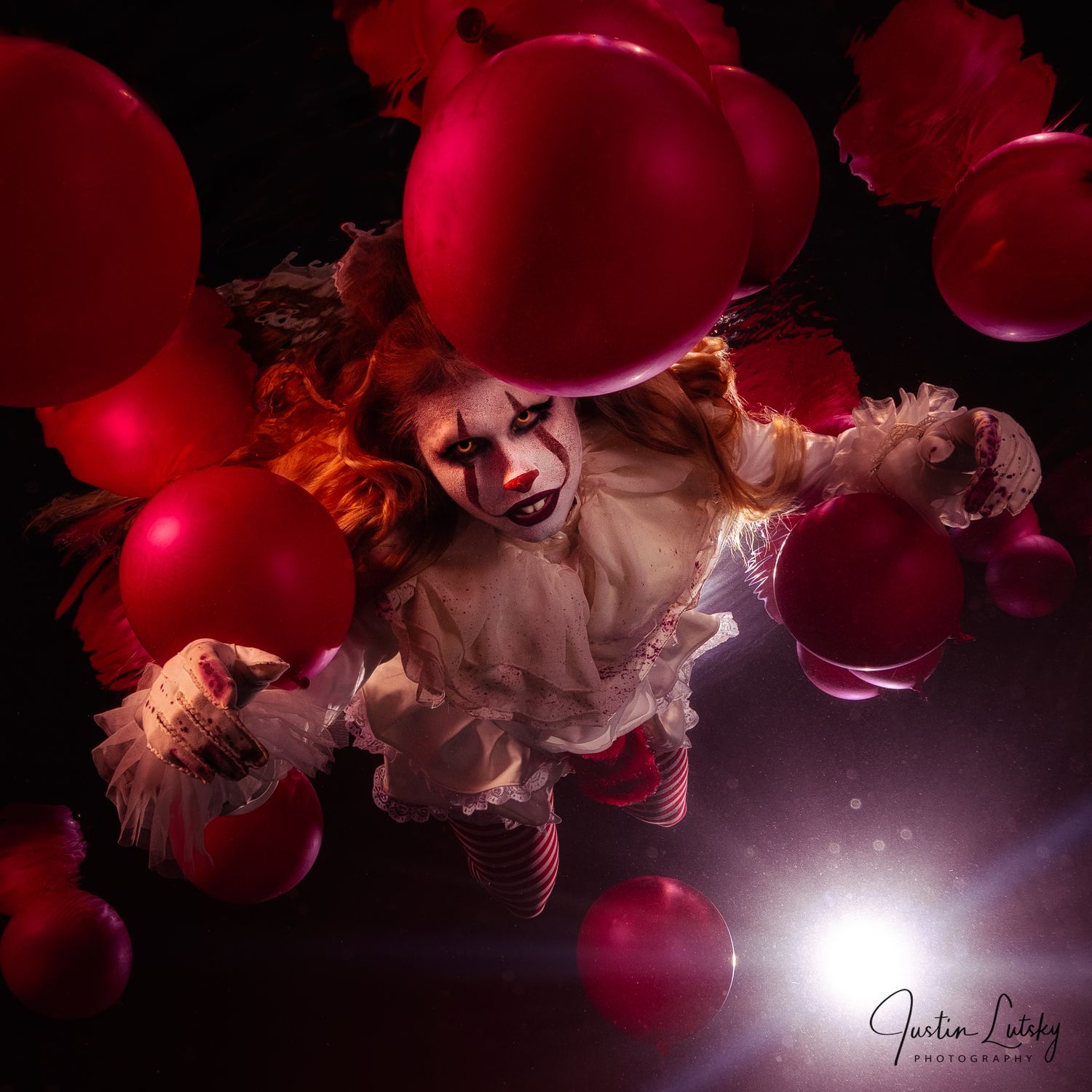 Creepy clown figure in white outfit with striped stockings floats among red balloons in dark atmospheric setting.
