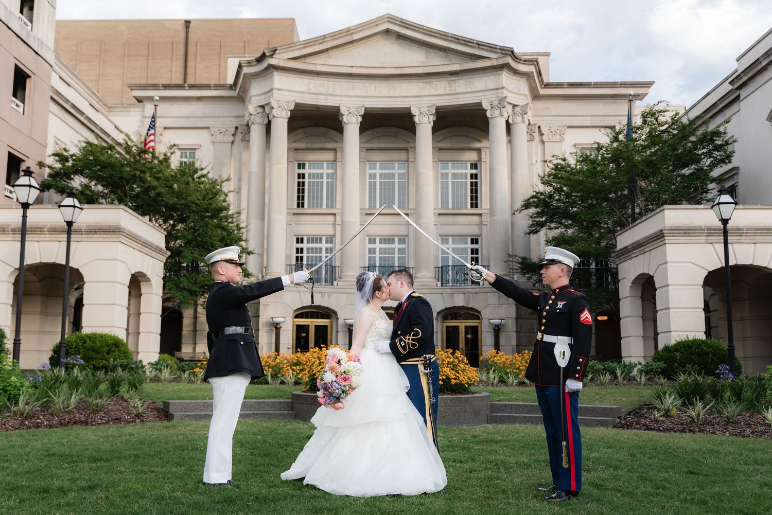 Military formal gathering with a bride in a flowing white gown on the lawn of a stately neoclassical building.