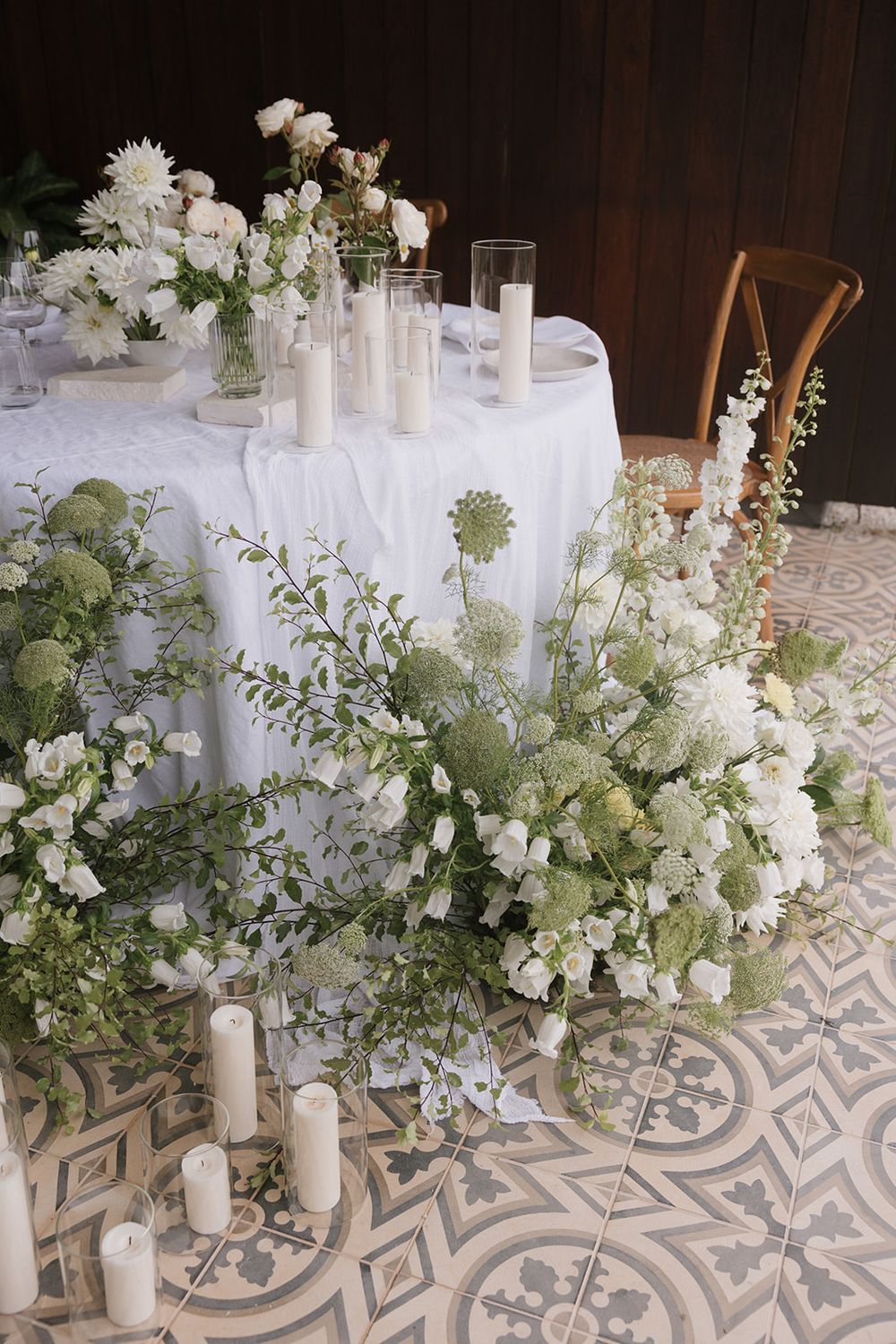 Elegant white and green floral centerpiece with candles on patterned tile.