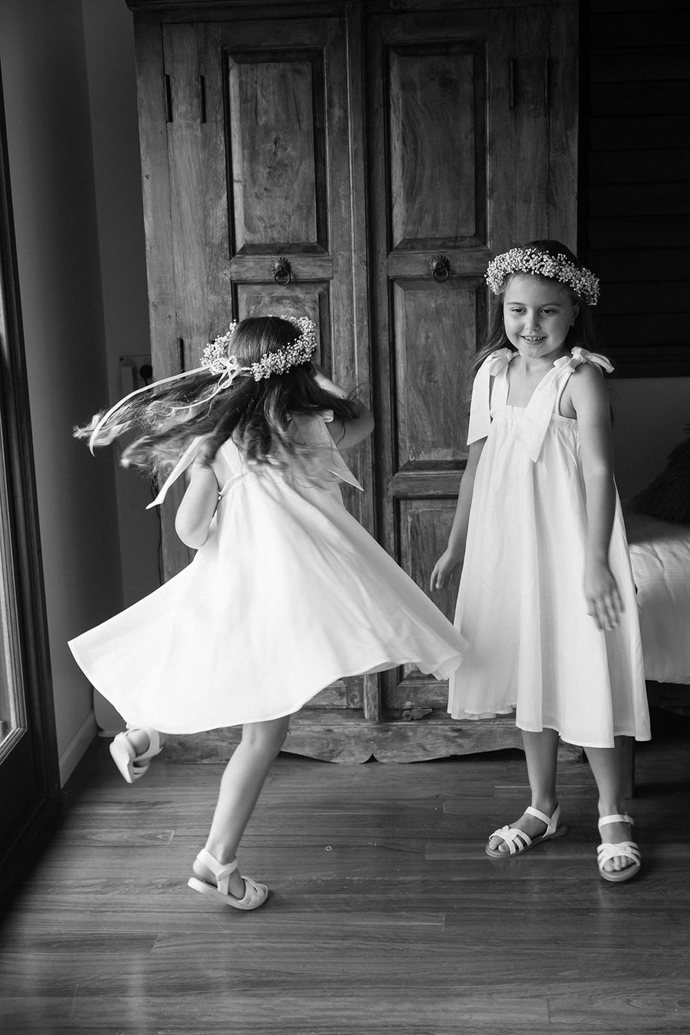 Black and white photograph of children in white dresses with flower crowns.