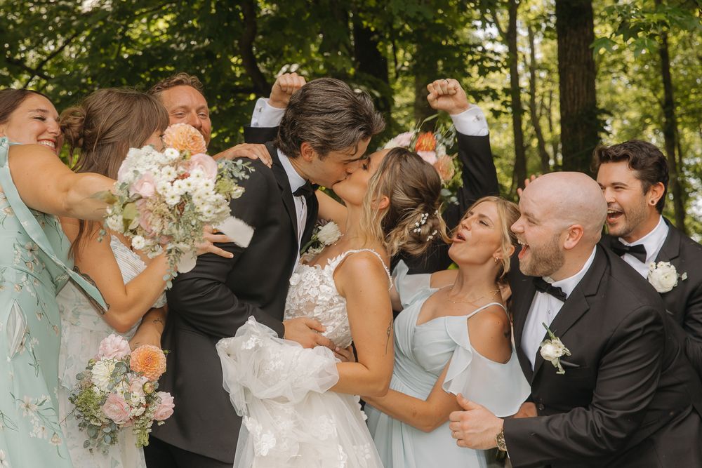 Wedding party celebrates together outdoors with joyful laughter and excitement during summer celebration.