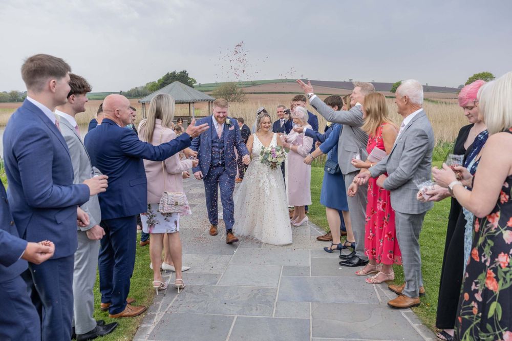 Wedding guests forming a celebratory arch on an outdoor patio during a sunny day celebration.