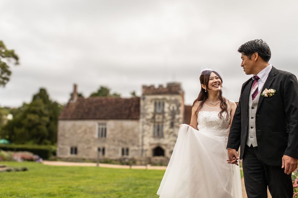 A bride and groom share a joyful moment together on the lawn of a historic stone castle estate.