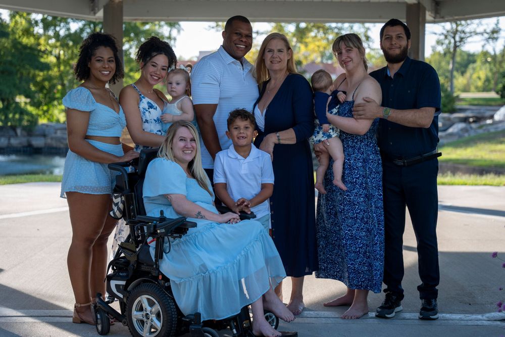 A diverse group of friends and family pose together outdoors for a group portrait.