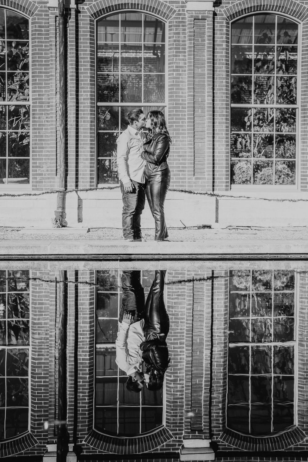 A creative black and white portrait with a reflection in water showing a couple's embrace.