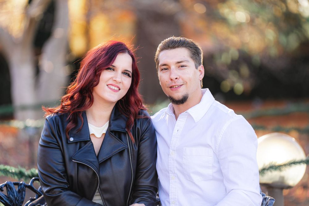 A couple sitting outdoors during an autumn photoshoot wearing contrasting black and white outfits.