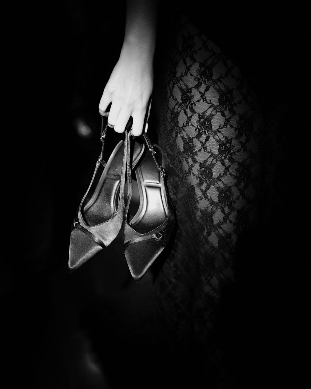 Black and white artistic photos of elegant high heels suspended against a dark textured damask pattern background.
