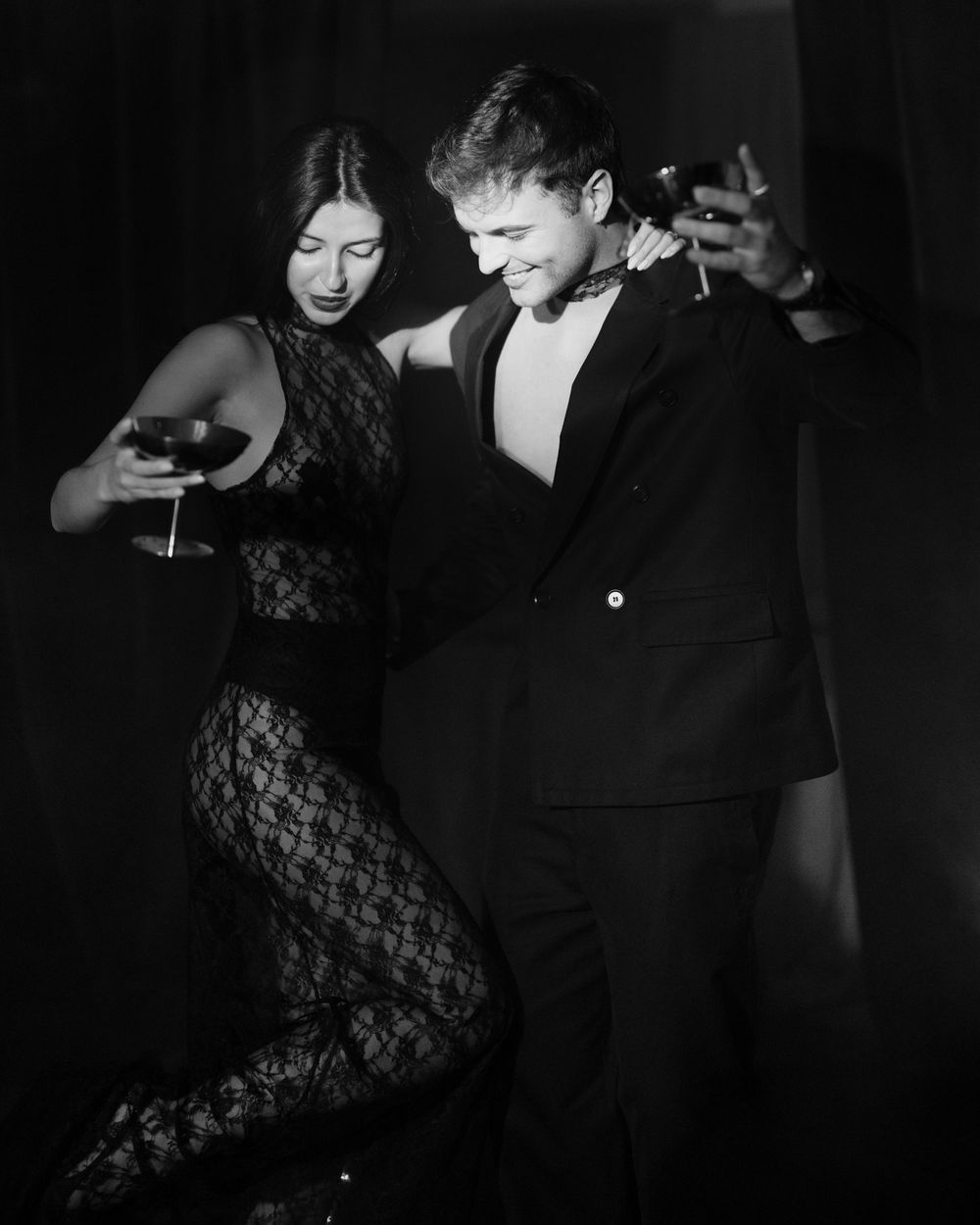 A couple dancing together in formal attire, captured in dramatic black and white lighting with film noir aesthetics.