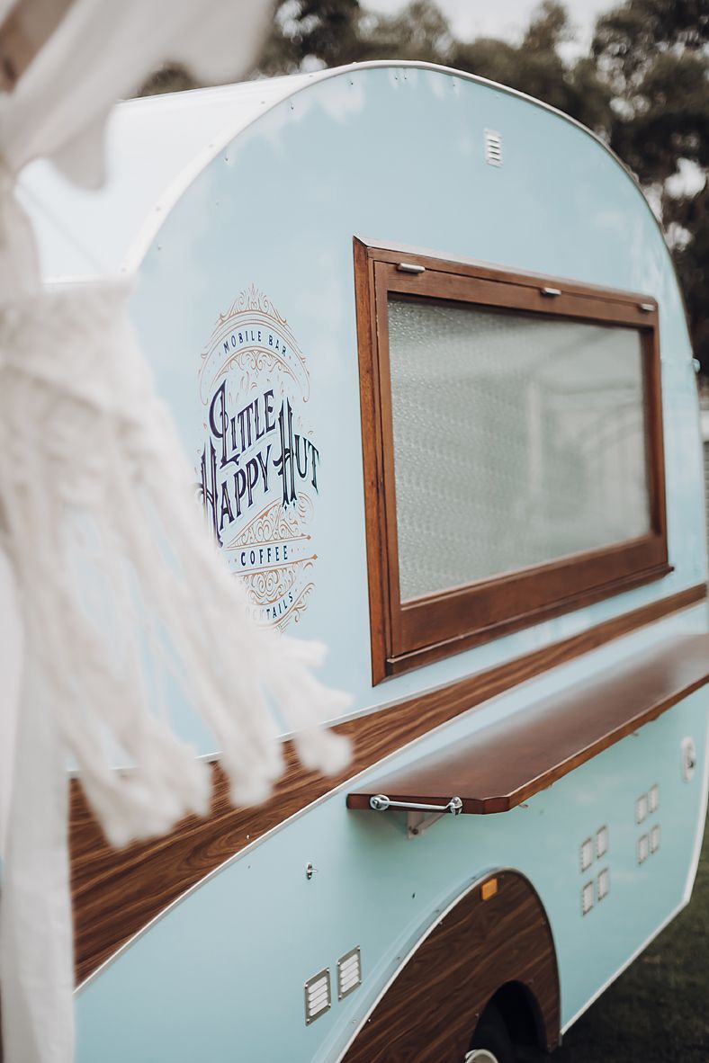 Vintage-style food truck window with wooden frame and light blue exterior showing "Little Happy Art" retro signage.