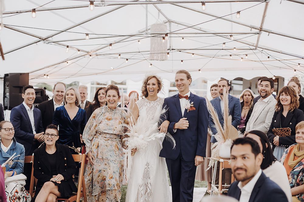 Wedding guests celebrate with confetti at an elegant outdoor reception under a white tent canopy.