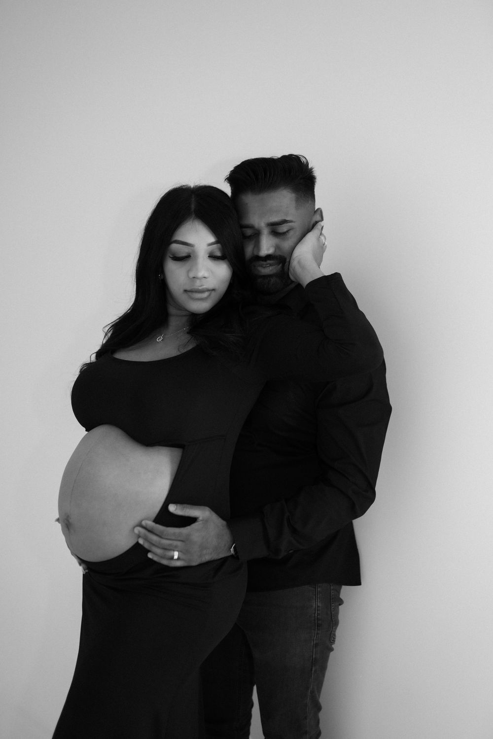 Black and white maternity photo series showing intimate couple poses with focus on the pregnant belly.