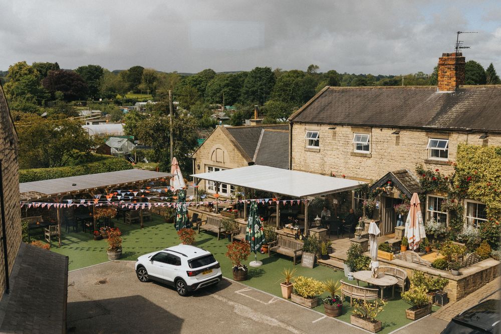 Panoramic view of stone buildings and event tents set up for an outdoor celebration in rural setting.