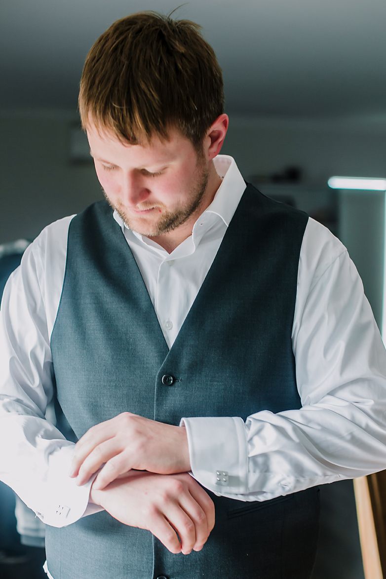Person wearing a white dress shirt and grey vest adjusts their sleeve cuff in a sequence of close-up shots.