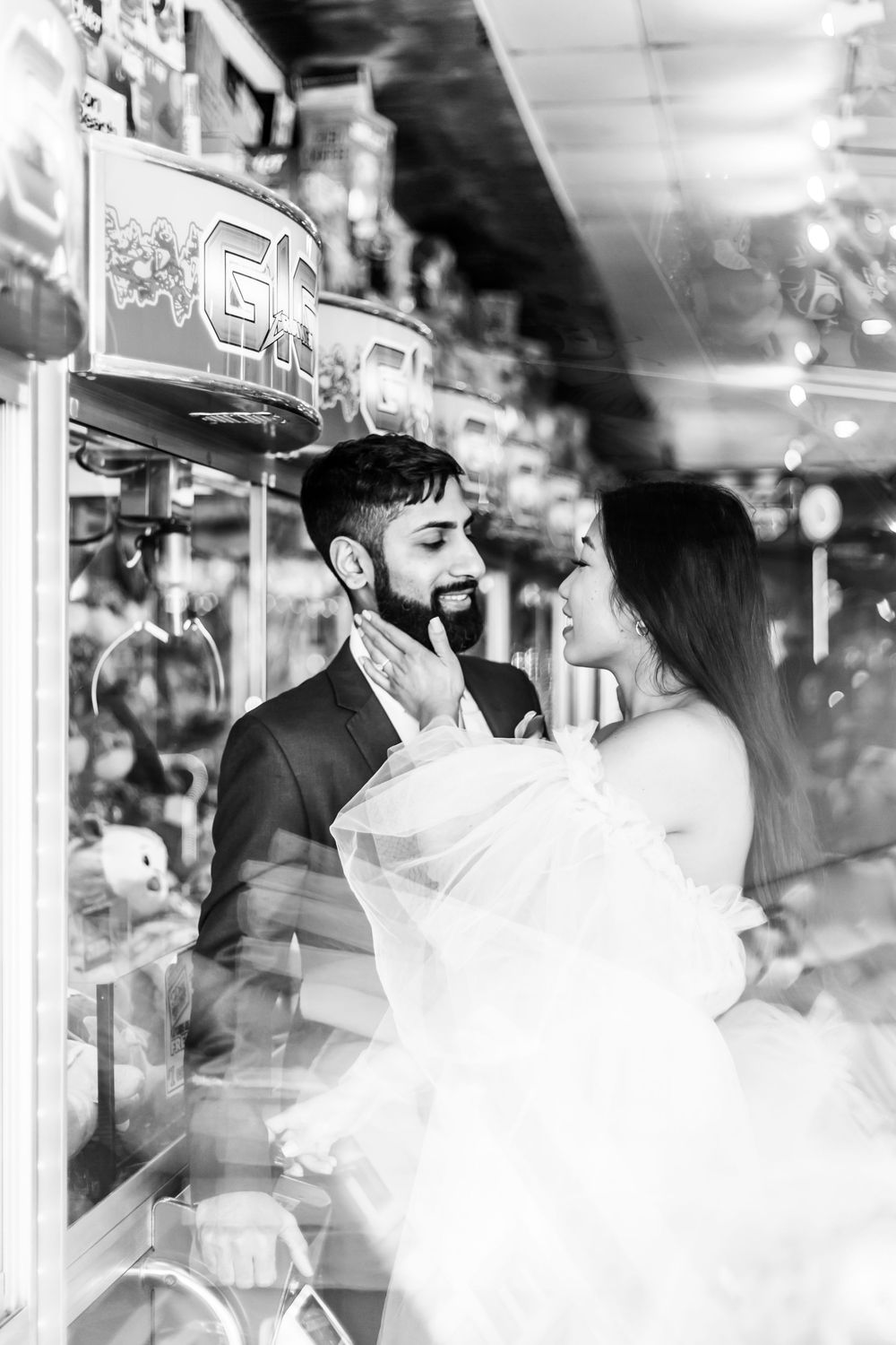 Black and white photo of couple in formal wear sharing a romantic moment in an indoor venue.