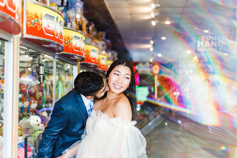 Couple laughing together in a brightly lit indoor venue with festive lighting.