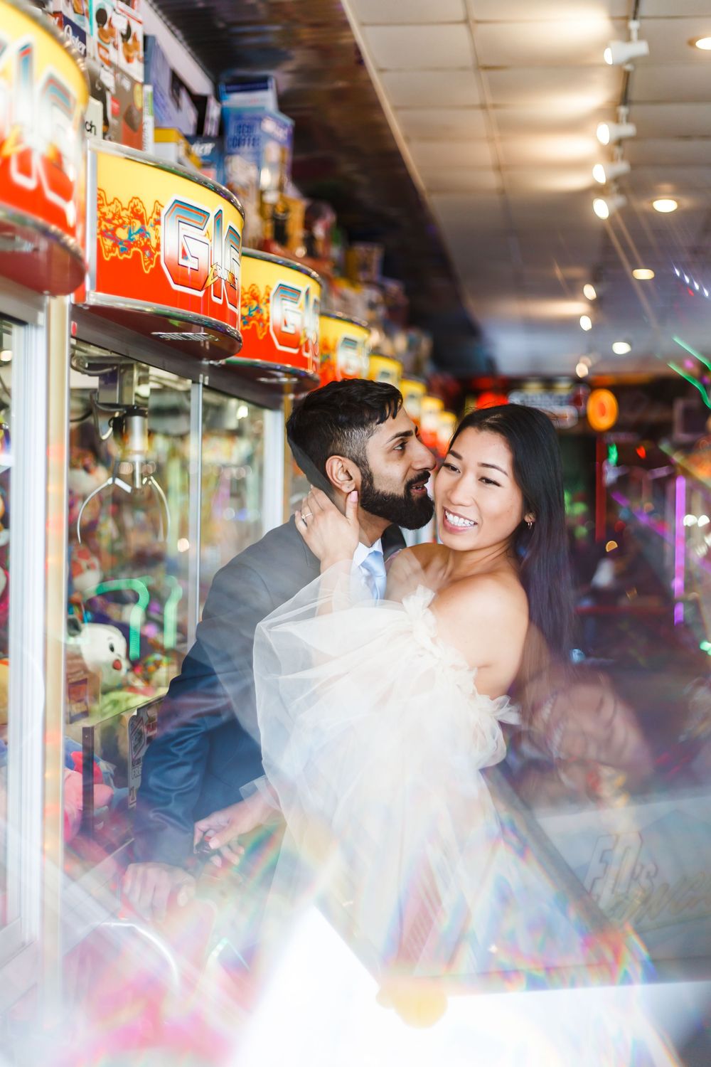 Couple having fun in a vibrant arcade setting with colorful lights and reflections.