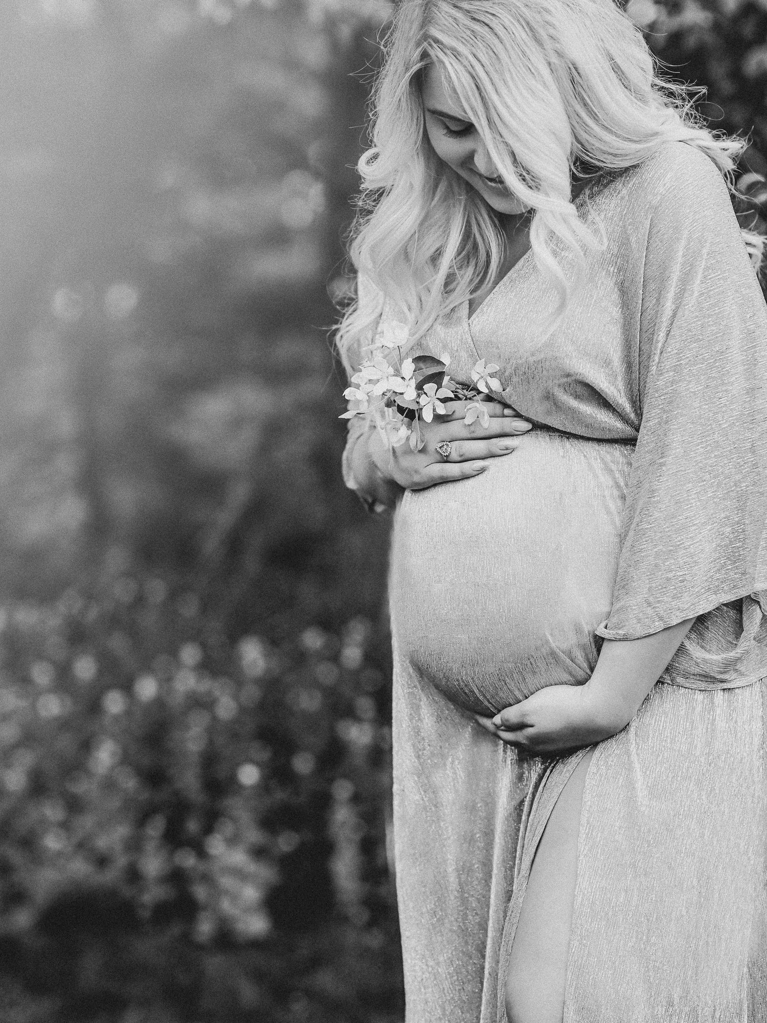 Black and white portrait photograph of a mother holding baby in matching grey sweaters during outdoor photoshoot.