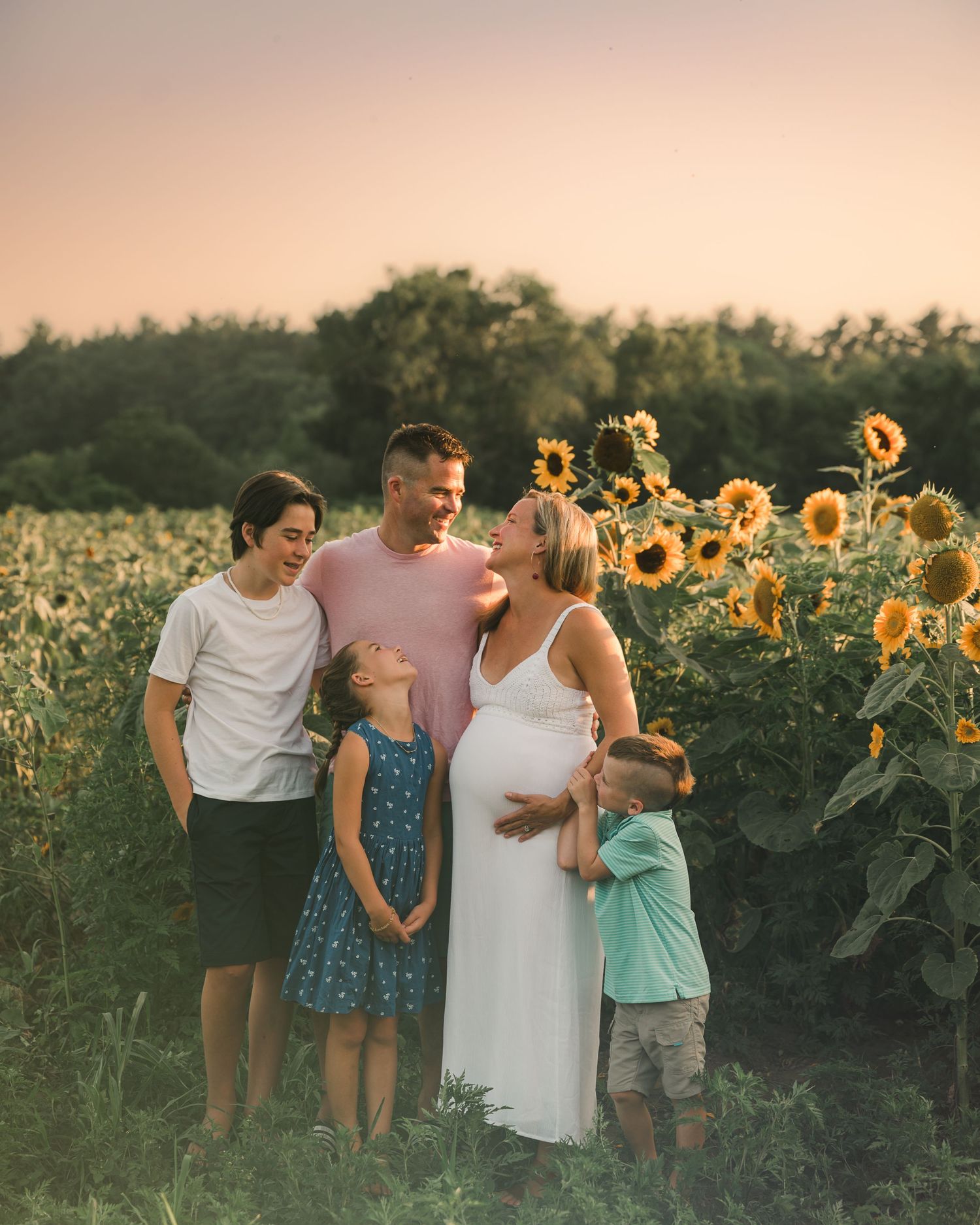 A golden-lit family photoshoot in a beautiful sunflower field during sunset creates a warm and joyful atmosphere.