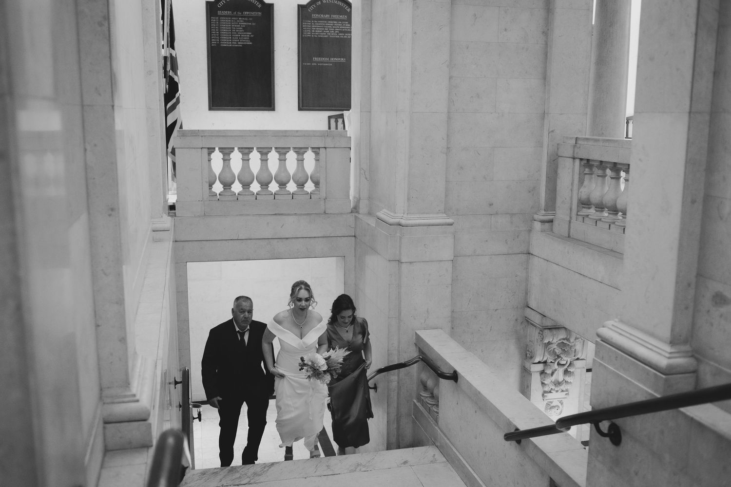 Architectural details of a bright indoor corridor with ornate white walls and people walking in the background.