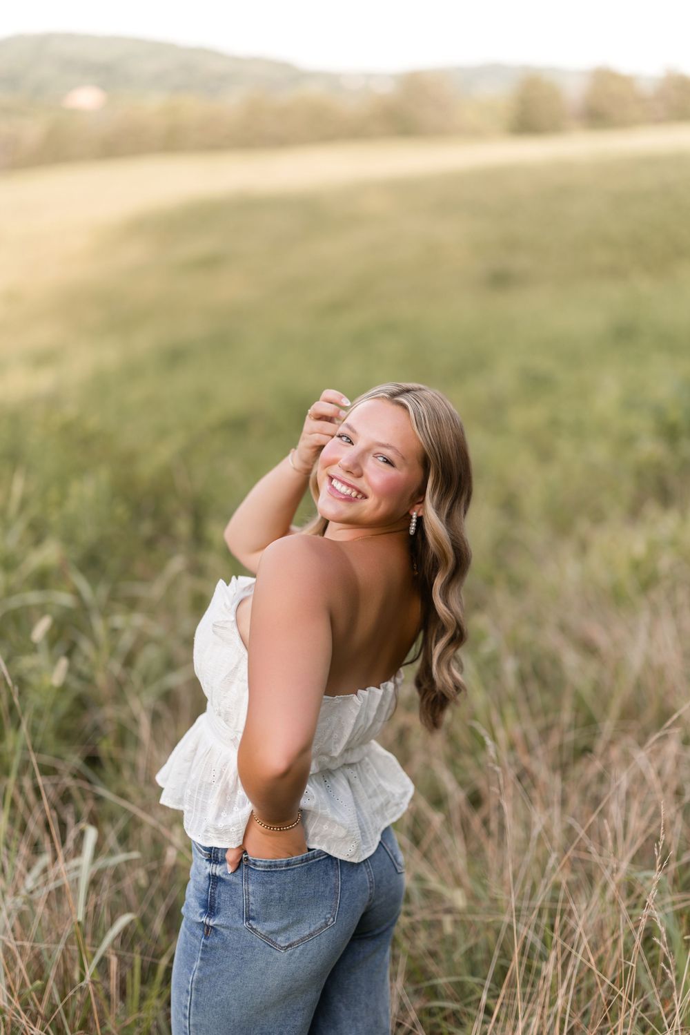 A joyful lifestyle portrait in a dreamy golden field with tall grass and soft sunset lighting.
