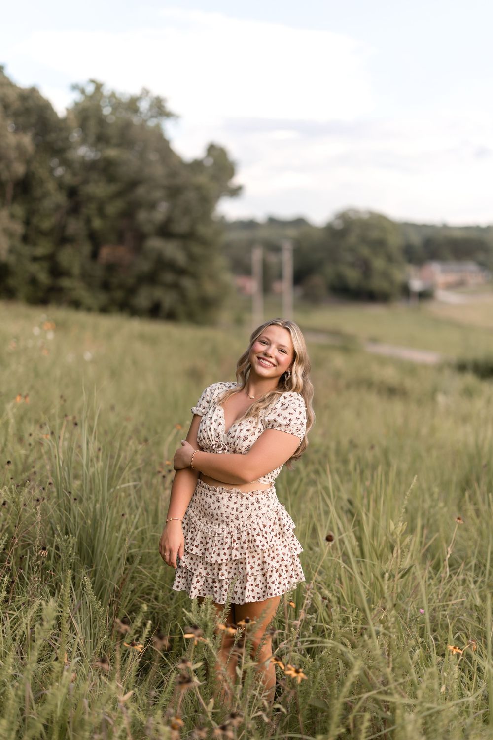 A person in a leopard print dress laughs joyfully while walking through a sun-lit grassy field.
