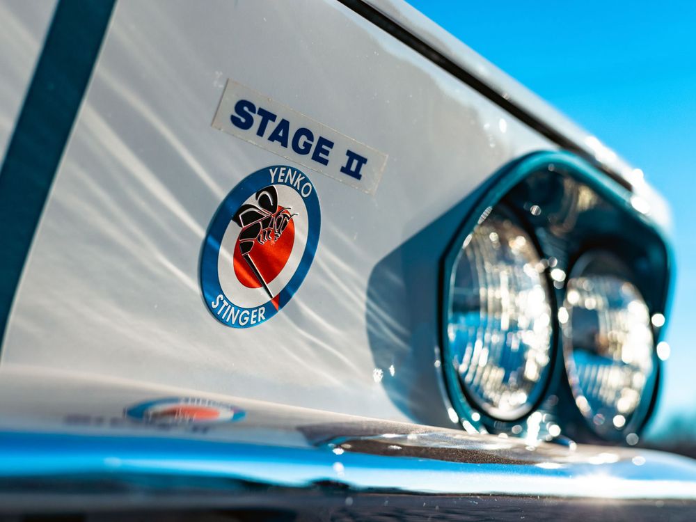 Stage II badge detail on white classic car body with dual headlights visible.