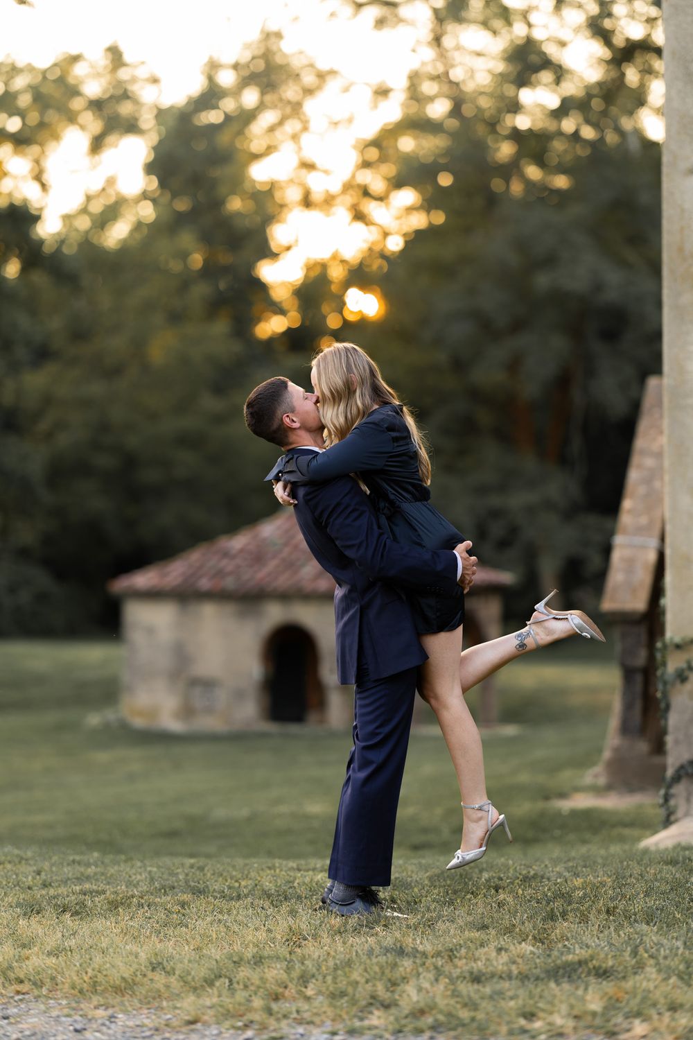 Joyful embrace with lifting pose against sunset garden backdrop.