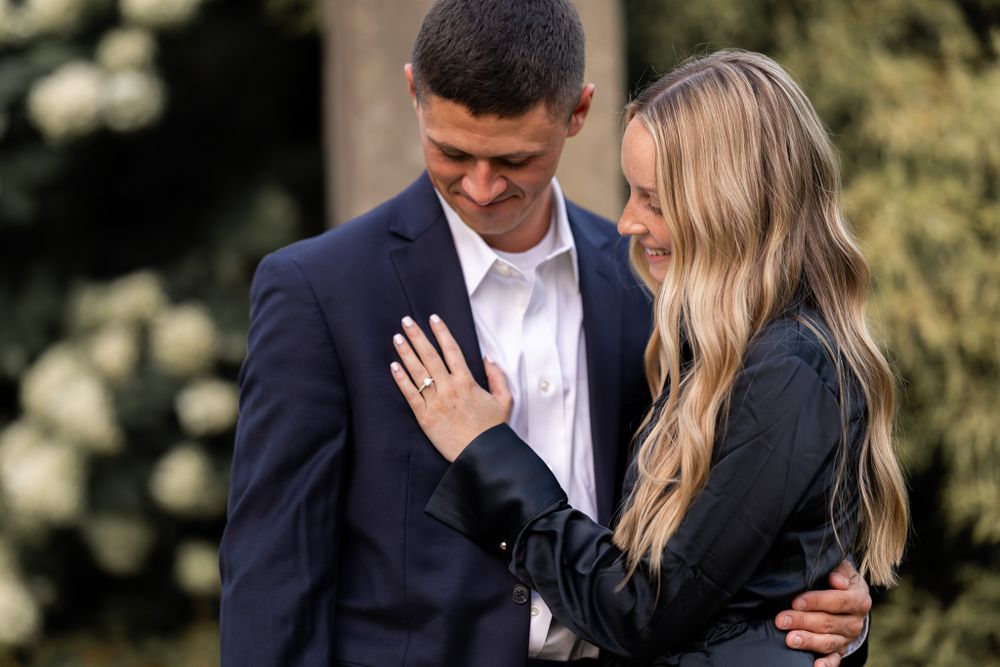 Engagement photo showing ring while couple embraces outdoors.