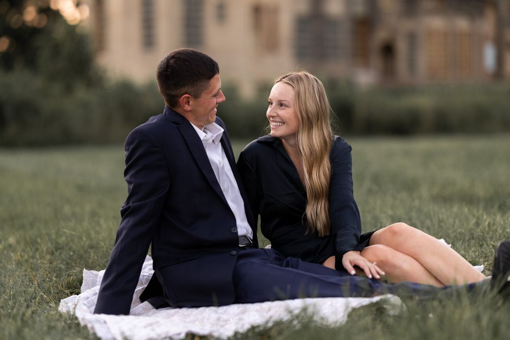 A couple enjoys a picnic on a blanket with a castle backdrop.