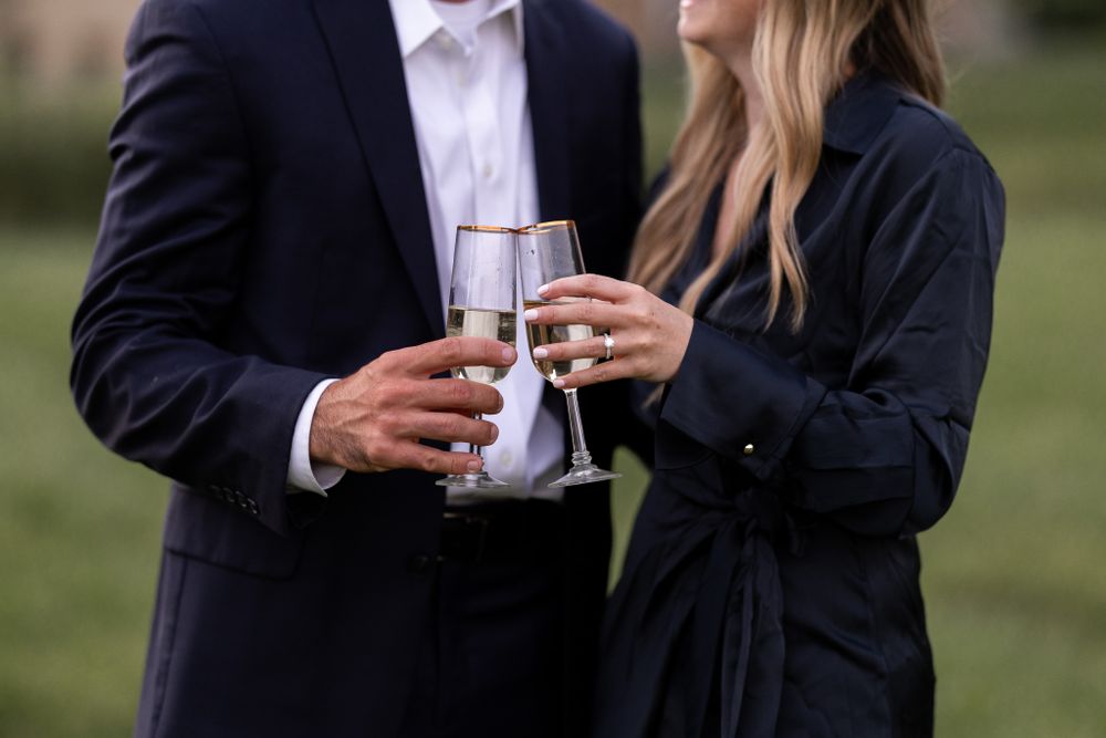 Two people clink champagne glasses together in an outdoor celebration.