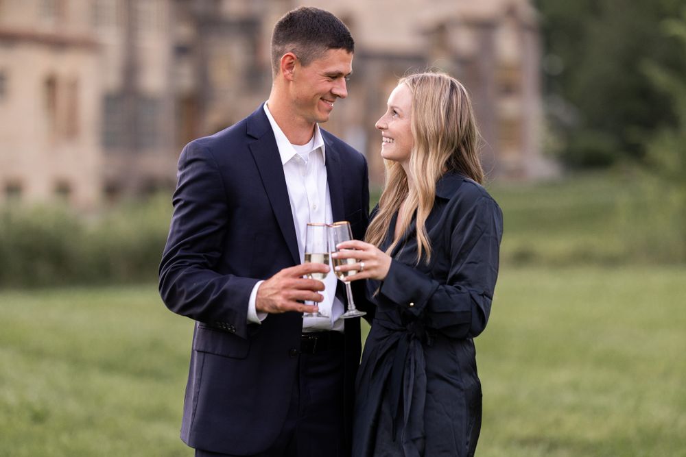 A couple shares an intimate moment while holding champagne glasses outdoors.