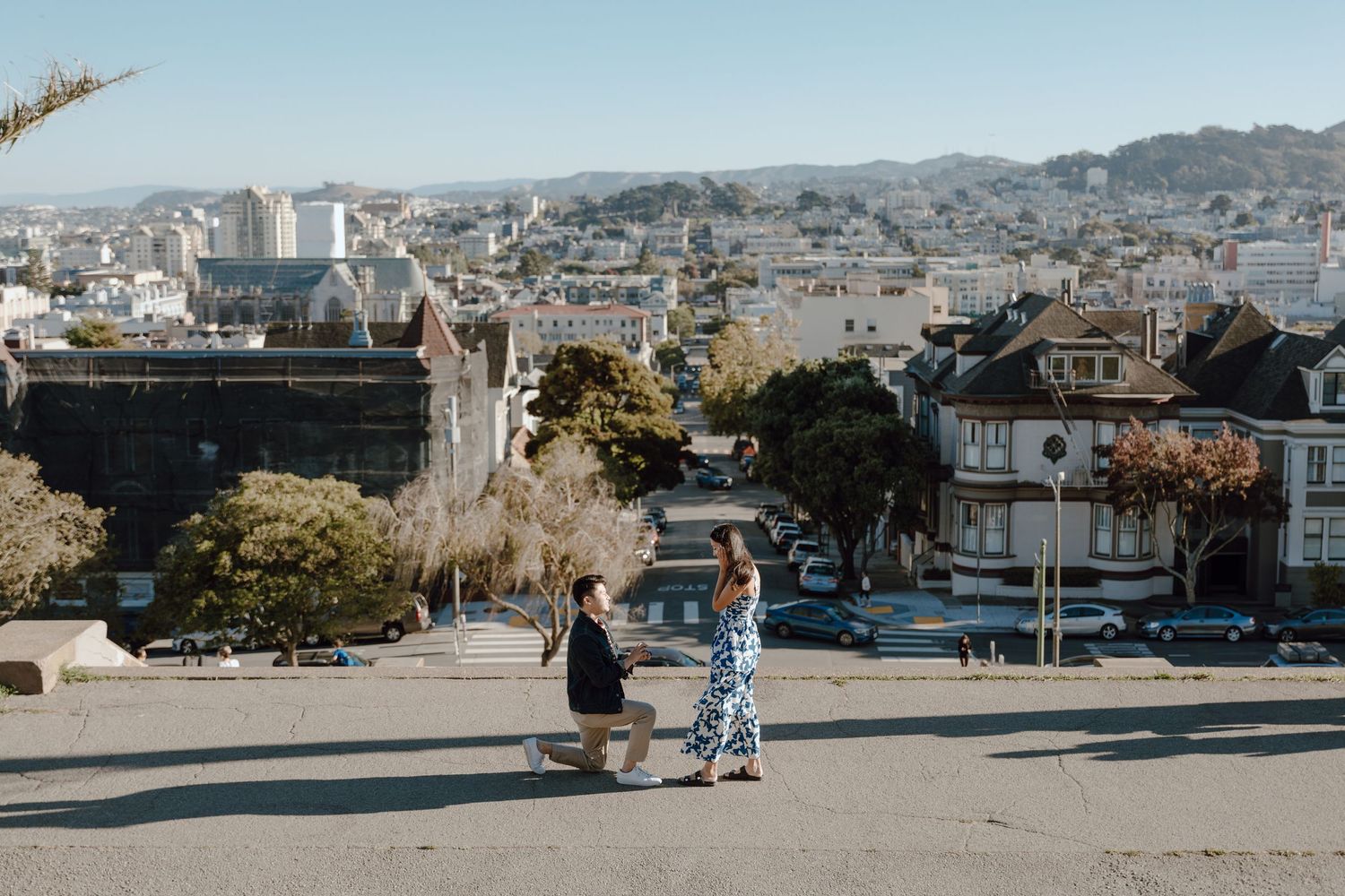 Scenic cityscape view of San Francisco from elevated viewpoint with people overlooking residential neighborhood.