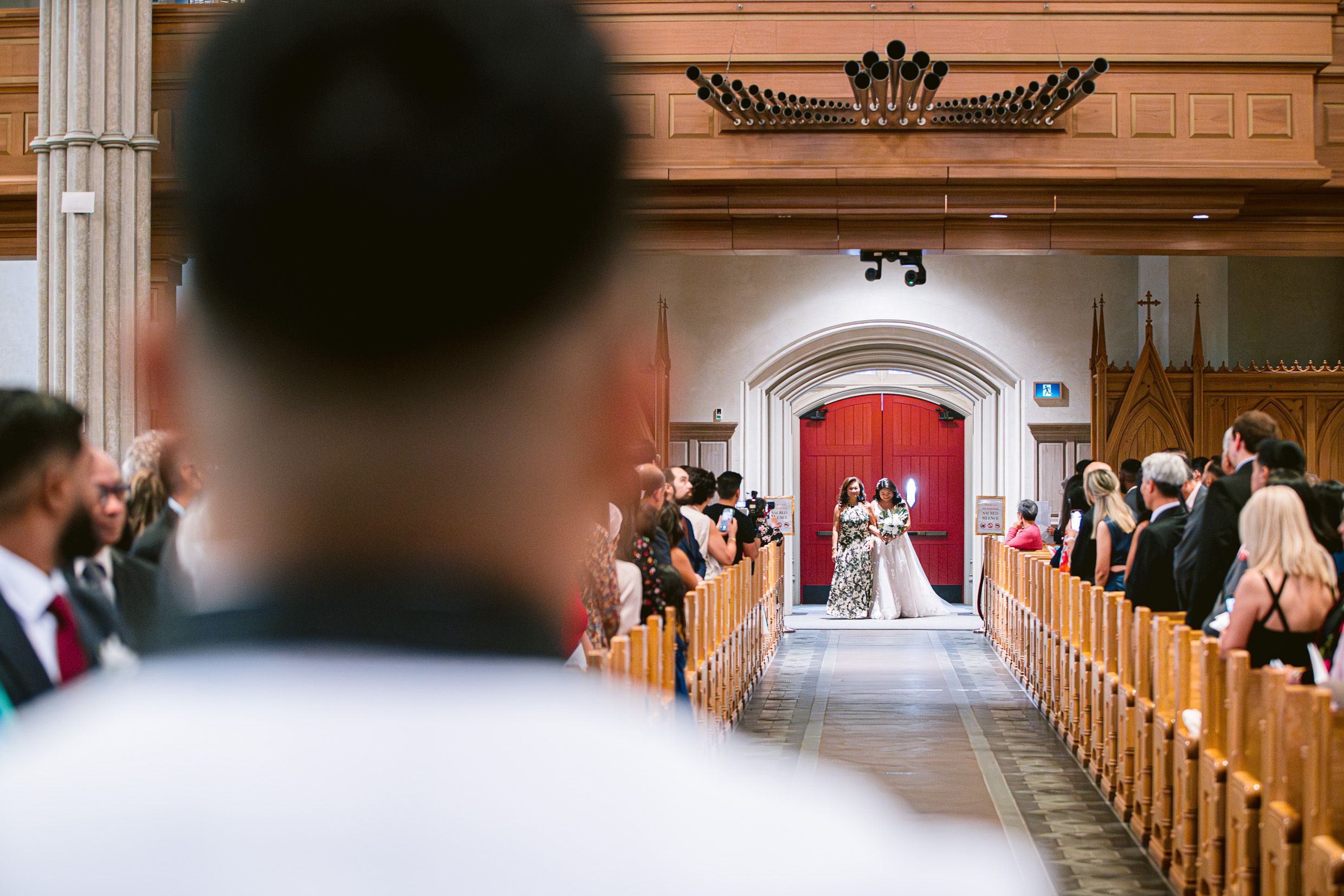 A wedding ceremony in progress inside an elegant church with guests seated in wooden pews.