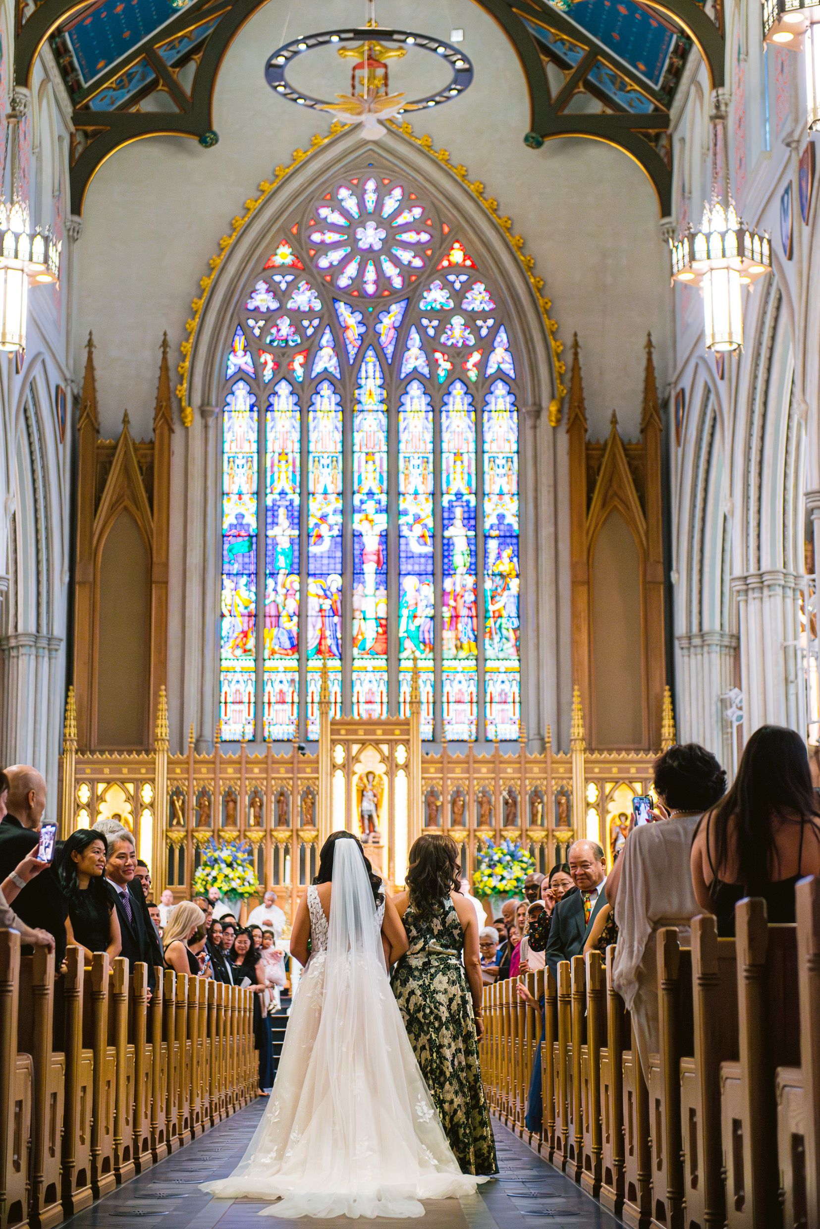 Beautiful stained glass window in a gothic church cathedral during a wedding ceremony with people in pews.