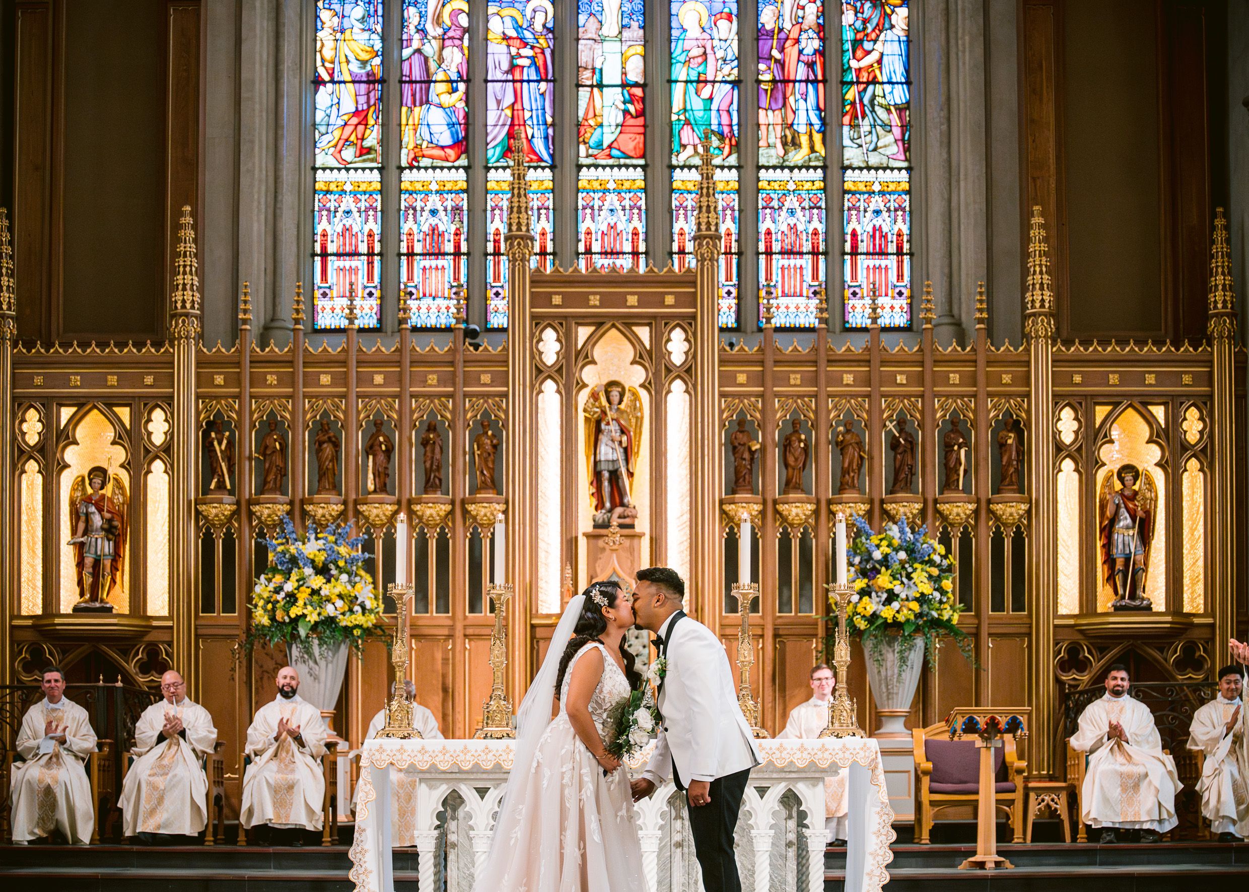 Church altar with ornate Gothic woodwork and stained glass windows during wedding ceremony.