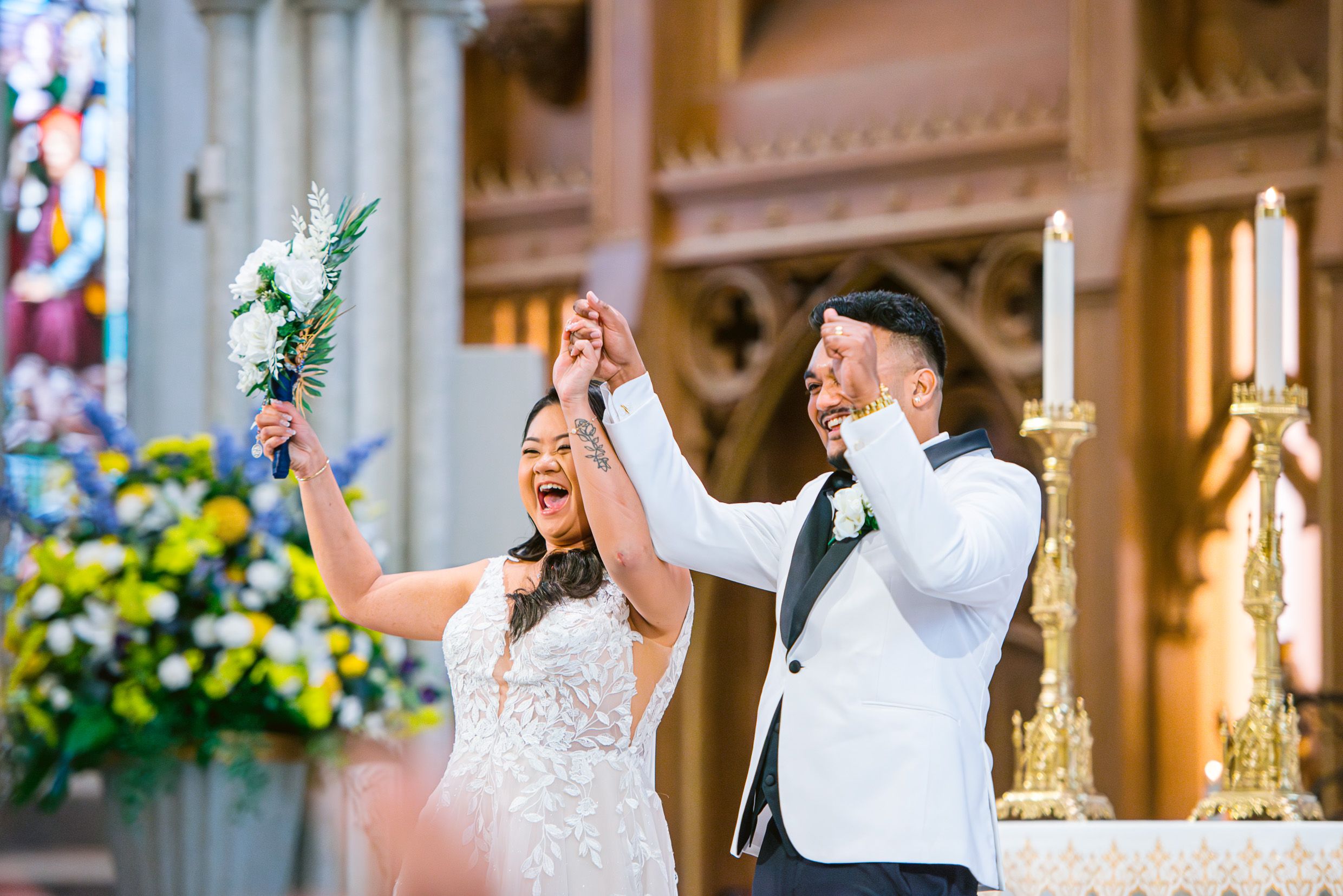 Happy newlyweds celebrate with raised arms at the altar after their wedding ceremony.