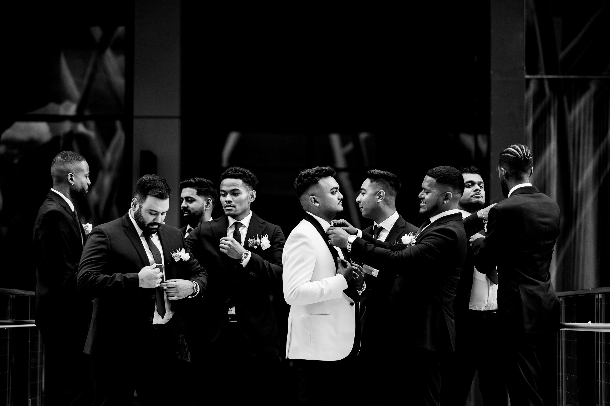 Black and white photo of groomsmen sharing laughs during wedding celebrations.