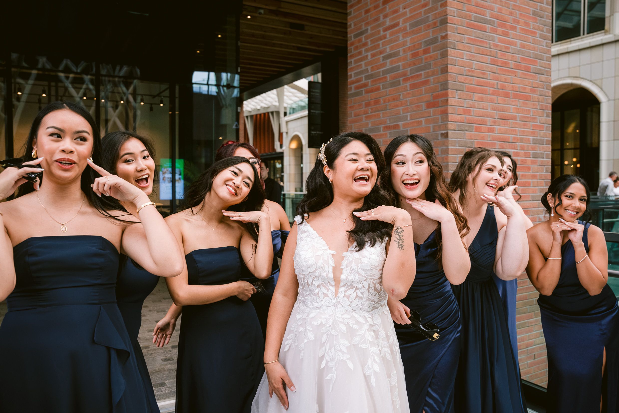 Wedding party in navy blue dresses posing together with joyful expressions.