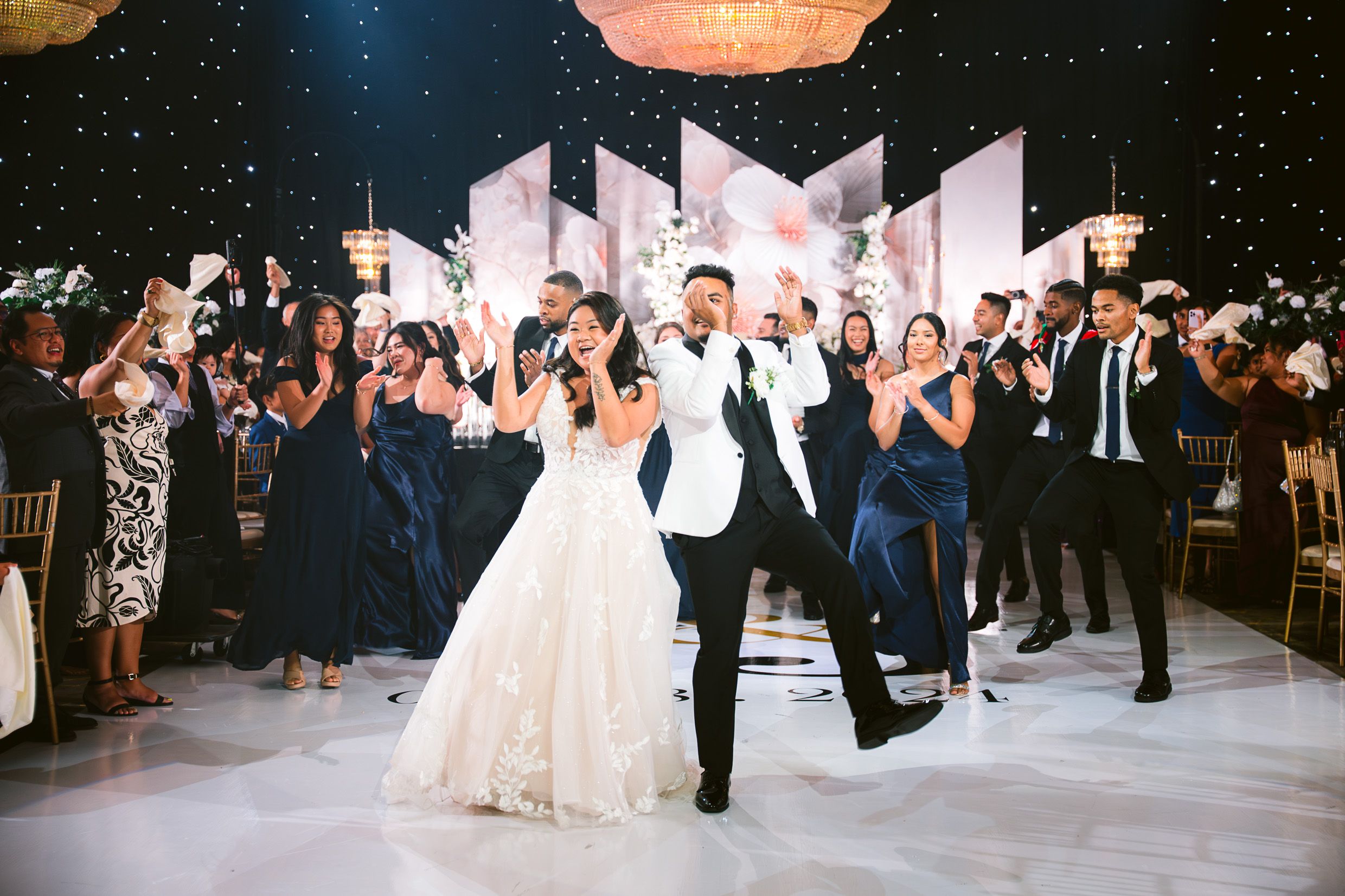 Wedding guests celebrate on the dance floor under sparkling decorations.