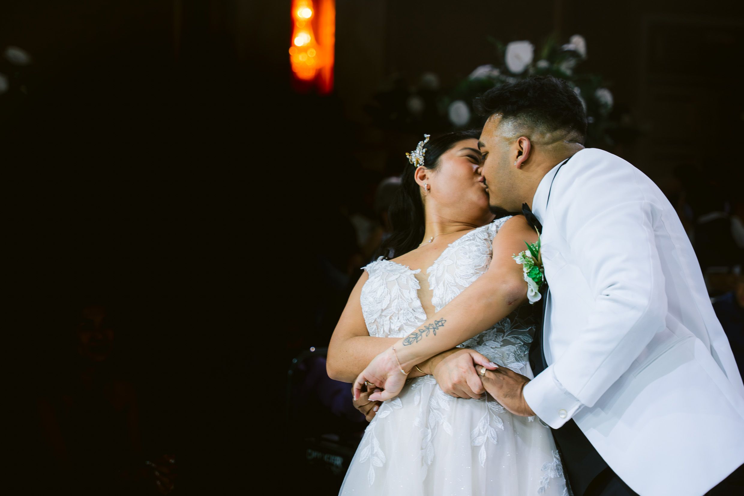 A romantic couple shares a tender moment during their wedding, with the bride in white and groom in a light suit.
